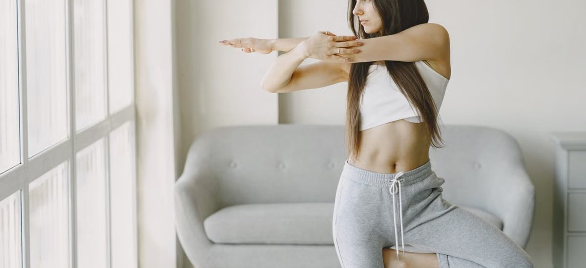 A woman performs a yoga pose at home, focusing on balance and tranquility.